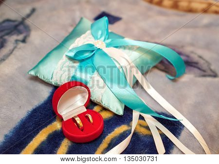 Gold wedding rings in a red box near the pincushion