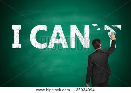 I can self motivation concept. Businessman wiping letter 'T off chalkboard so that it reads i can