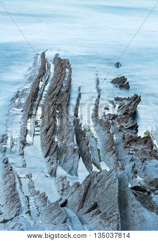 Twilight Ocean Coast With Ribbed Stratiform Rock.