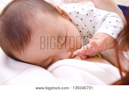 Six months old asian baby boy drinking breastmilk
