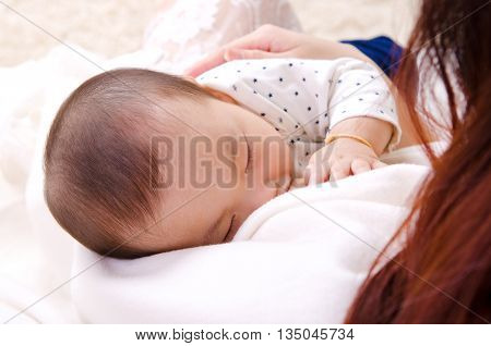 Six months old asian baby boy drinking breastmilk