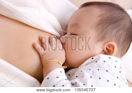 Six months old asian baby boy drinking breastmilk