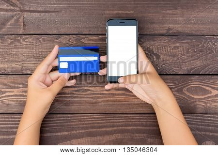 closeup hand use phone and credit card on table top view
