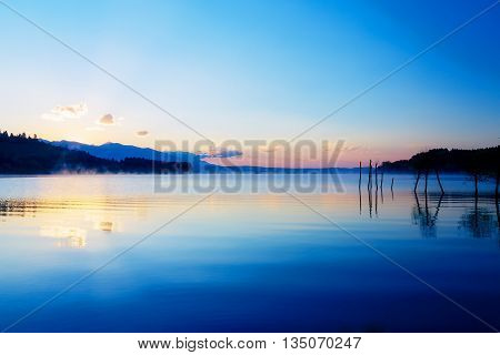 Beautiful Lake View In Morning Fog With Mystic Mountains And Tre