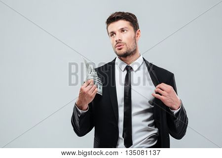 Tired young busnessman feeling hot and fanning with money over white background