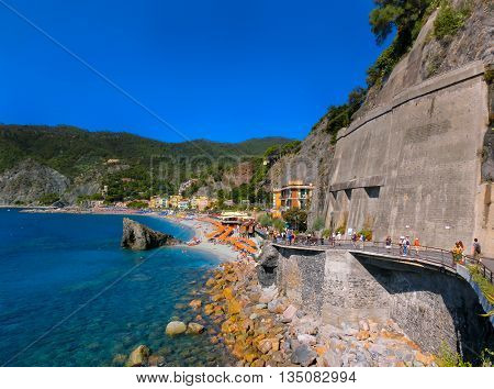 MONTEROSSO, ITALY - SEPTEMBER 09, 2015: People on the coastline of Monterosso in Italy. Monterosso is one of five famous coastline villages in the Cinque Terre National Park.