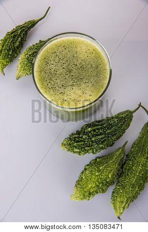 Herbal juice of green momodica in a glass with sliced vegetables, karela juice or bitter gourd juice