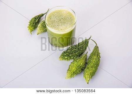 Herbal juice of green momodica in a glass with sliced vegetables, karela juice or bitter gourd juice