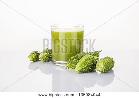 Herbal juice of green momodica in a glass with sliced vegetables, karela juice or bitter gourd juice