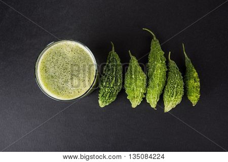 Herbal juice of green momodica in a glass with sliced vegetables, karela juice or bitter gourd juice
