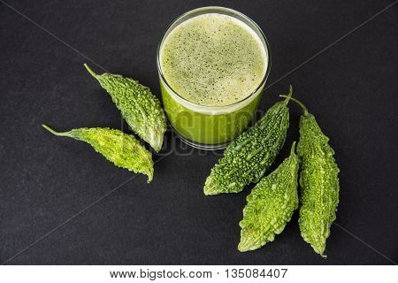 Herbal juice of green momodica in a glass with sliced vegetables, karela juice or bitter gourd juice