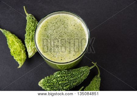 Herbal juice of green momodica in a glass with sliced vegetables, karela juice or bitter gourd juice