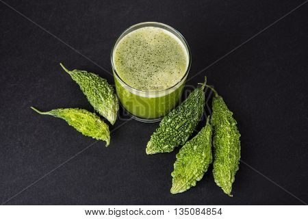 Herbal juice of green momodica in a glass with sliced vegetables, karela juice or bitter gourd juice