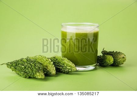 Herbal juice of green momodica in a glass with sliced vegetables, karela juice or bitter gourd juice