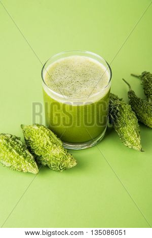 Herbal juice of green momodica in a glass with sliced vegetables, karela juice or bitter gourd juice