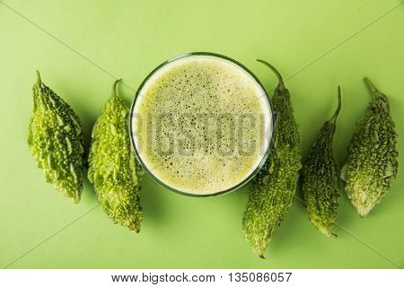 Herbal juice of green momodica in a glass with sliced vegetables, karela juice or bitter gourd juice