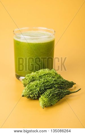 Herbal juice of green momodica in a glass with sliced vegetables, karela juice or bitter gourd juice