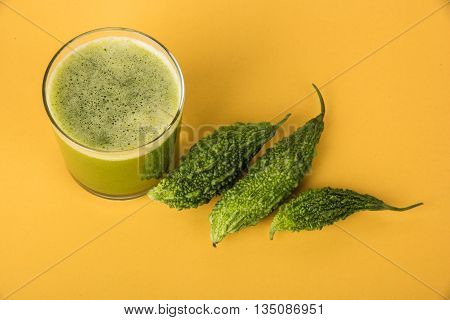 Herbal juice of green momodica in a glass with sliced vegetables, karela juice or bitter gourd juice