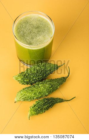 Herbal juice of green momodica in a glass with sliced vegetables, karela juice or bitter gourd juice