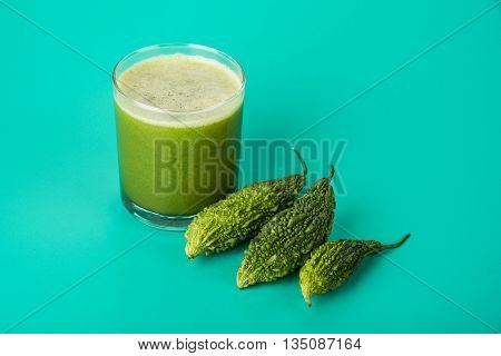 Herbal juice of green momodica in a glass with sliced vegetables, karela juice or bitter gourd juice