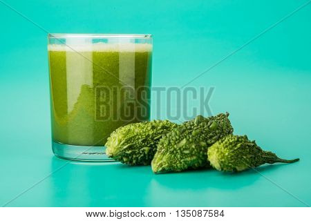 Herbal juice of green momodica in a glass with sliced vegetables, karela juice or bitter gourd juice