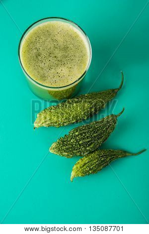 Herbal juice of green momodica in a glass with sliced vegetables, karela juice or bitter gourd juice