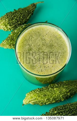 Herbal juice of green momodica in a glass with sliced vegetables, karela juice or bitter gourd juice