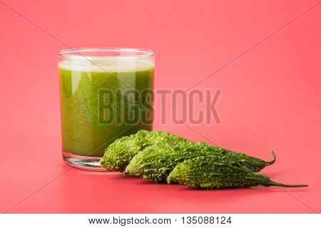 Herbal juice of green momodica in a glass with sliced vegetables, karela juice or bitter gourd juice