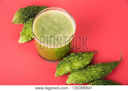 Herbal juice of green momodica in a glass with sliced vegetables, karela juice or bitter gourd juice