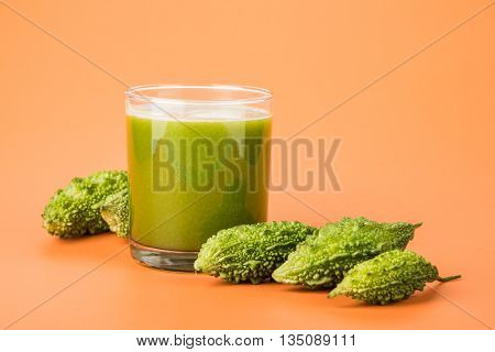 Herbal juice of green momodica in a glass with sliced vegetables, karela juice or bitter gourd juice