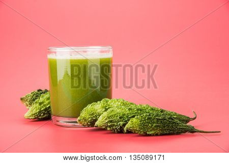 Herbal juice of green momodica in a glass with sliced vegetables, karela juice or bitter gourd juice