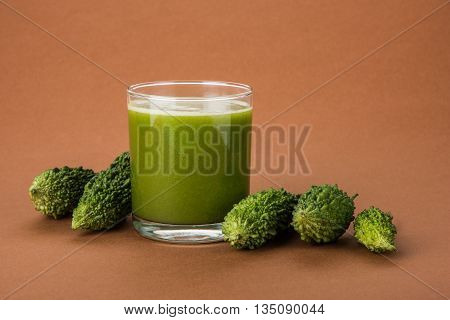 Herbal juice of green momodica in a glass with sliced vegetables, karela juice or bitter gourd juice