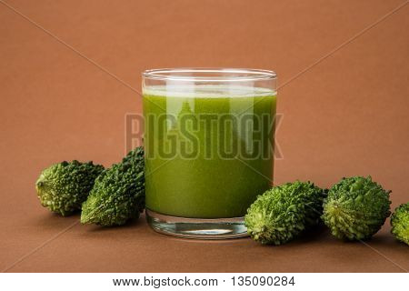 Herbal juice of green momodica in a glass with sliced vegetables, karela juice or bitter gourd juice