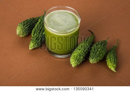 Herbal juice of green momodica in a glass with sliced vegetables, karela juice or bitter gourd juice