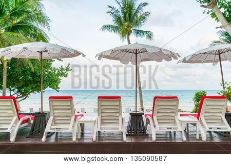 Beautiful beach chairs with umbrella around outdoor swimming pool neary sand and sea