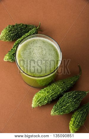 Herbal juice of green momodica in a glass with sliced vegetables, karela juice or bitter gourd juice