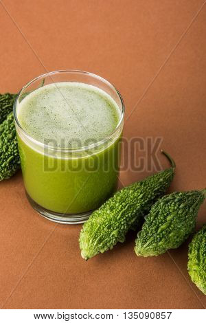 Herbal juice of green momodica in a glass with sliced vegetables, karela juice or bitter gourd juice
