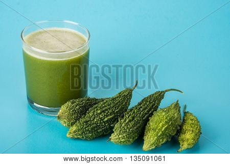 Herbal juice of green momodica in a glass with sliced vegetables, karela juice or bitter gourd juice