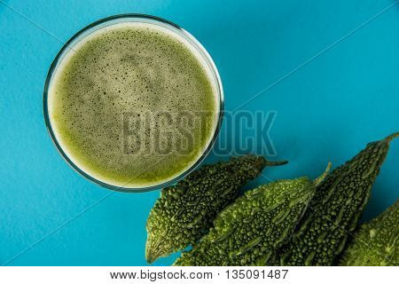 Herbal juice of green momodica in a glass with sliced vegetables, karela juice or bitter gourd juice