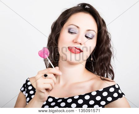 Portrait of happy beautiful young woman licking chupa chups. pretty woman with heart shaped lollipop.