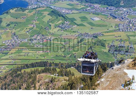 Mt. Stanserhorn, Switzerland - 7 May, 2016: people in a gondola of the Stanserhorn Cabrio cable car approaching the station on the top of the mountain. Stanserhorn Cabrio is the the world's first double deck open top cable car.