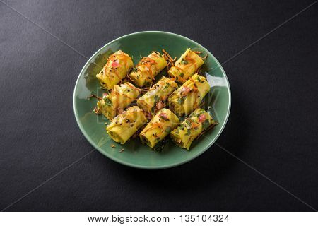 khandvi is a gujarati snack from India which is made with gram flour and curds tempered with sesame seeds and mustard seeds also known as Surali chya Vadya/Stuffed Khandvi, selective focus