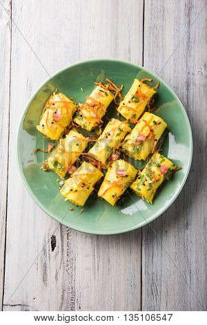 khandvi is a gujarati snack from India which is made with gram flour and curds tempered with sesame seeds and mustard seeds also known as Surali chya Vadya/Stuffed Khandvi, selective focus