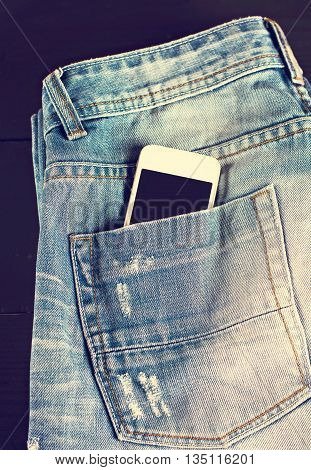 jeans and mobile phone on wooden boards. Phone in your pocket jeans