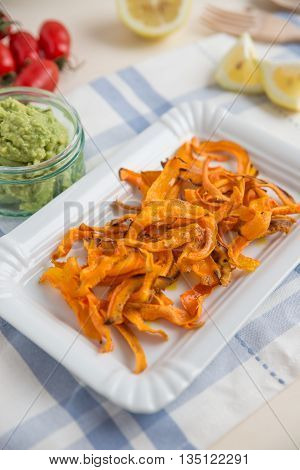 Healthy organic carrot vegetable chips with guacamole dip
