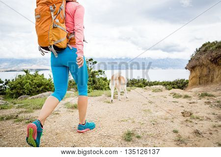 Woman hiking with akita inu dog on seaside trail. Recreation and healthy lifestyle outdoors in summer mountains and sea nature. Beautiful inspirational landscape. Trekking and activity concept.