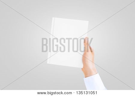 Hand in white shirt sleeve holding closed blank book cover mock up in the hand. Book front holding in sleeve shirt hand. Vertical catalogue template mock up hold in arm. Clear notebook cover.
