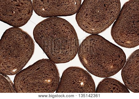 Slices of black rye bread on a white background. Food background. Pattern.