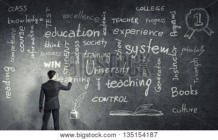 Rear view of man drawing education concept on blackboard with chalk