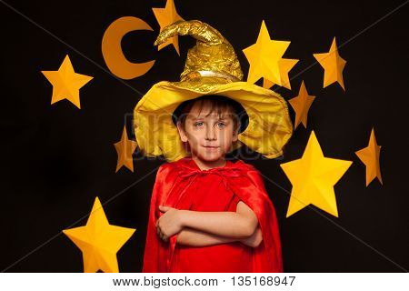 Five years old boy in sky watcher costume among big yellow paper stars and moon